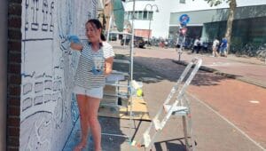 Marion Hoogendijk maakt muurschildering aan Asvest met zelfgemaakte verf